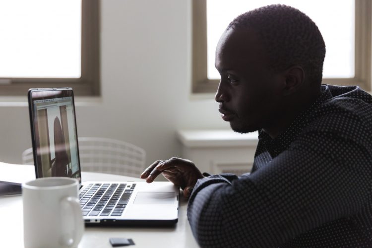 A man sits at a computer in a video meeting