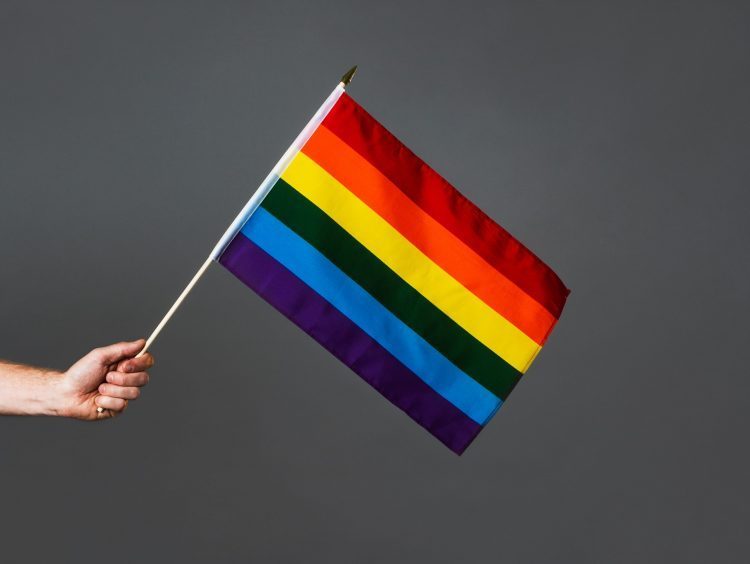 A hand holds a pride flag